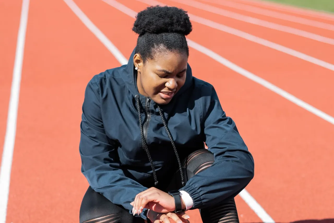 An athlete checking a sports smartwatch on a running track